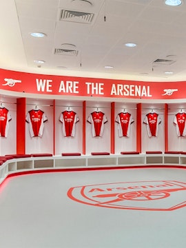 Arsenal FC Emirates Stadium locker room with team jerseys displayed.