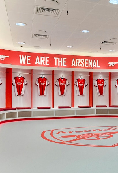 Arsenal FC Emirates Stadium locker room with team jerseys displayed.