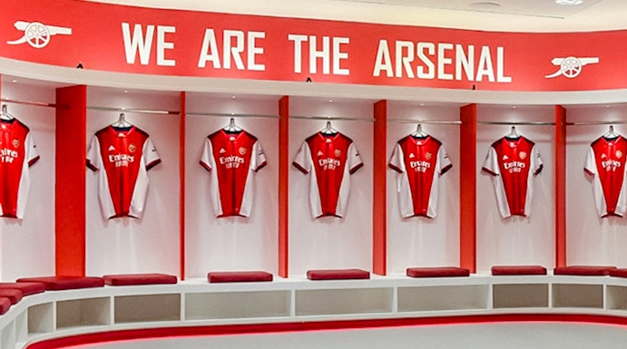 Arsenal FC Emirates Stadium locker room with team jerseys displayed.