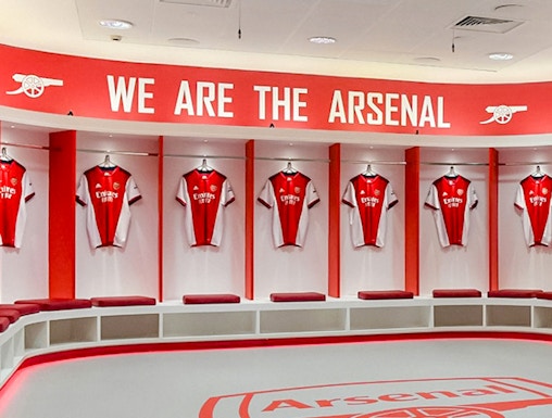 Arsenal FC Emirates Stadium locker room with team jerseys displayed.