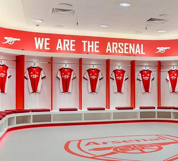 Arsenal FC Emirates Stadium locker room with team jerseys displayed.