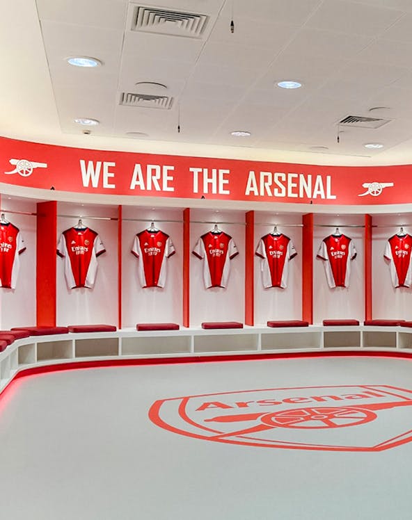 Arsenal FC Emirates Stadium locker room with team jerseys displayed.