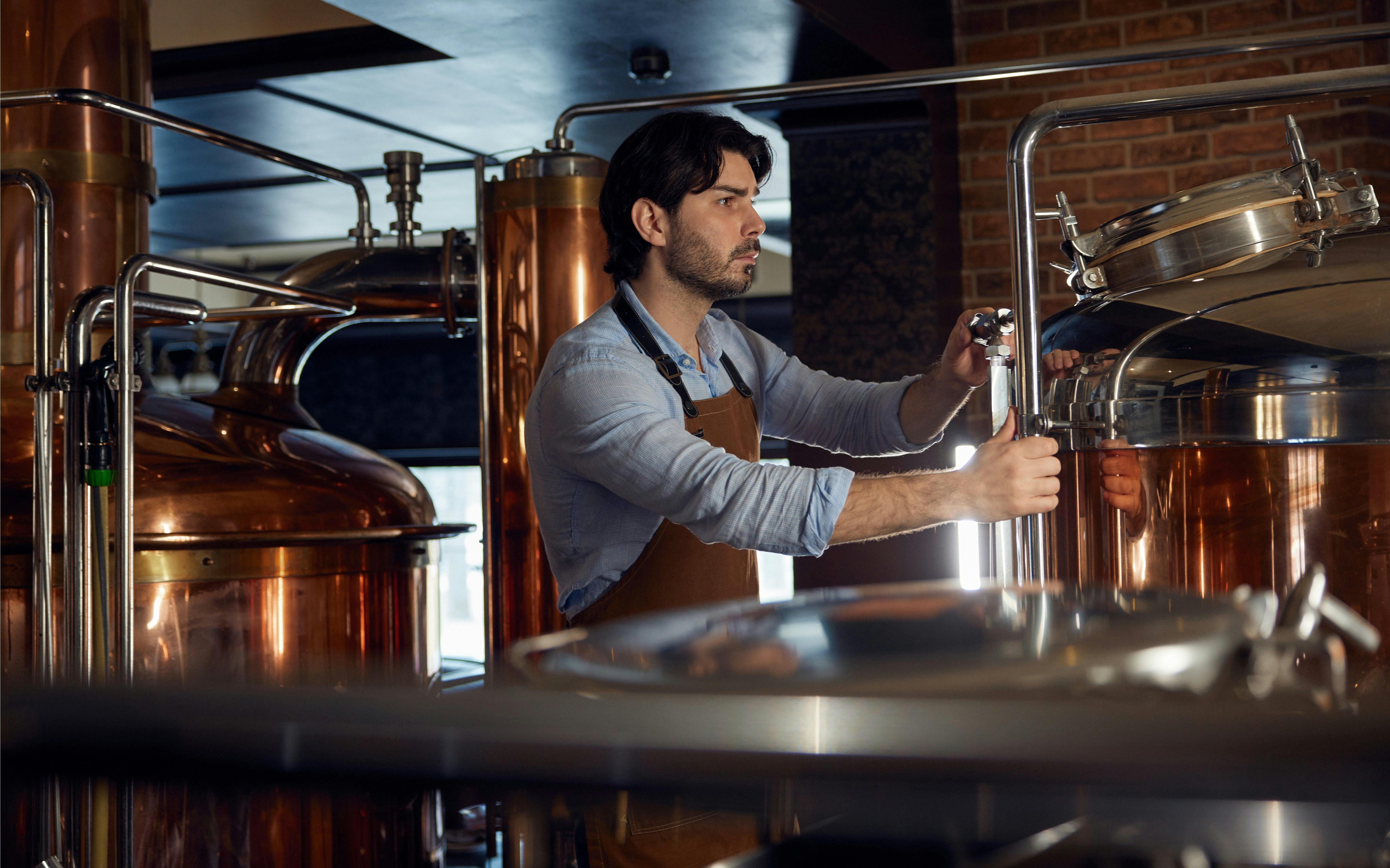 Man operating equipment at a whiskey distillery.