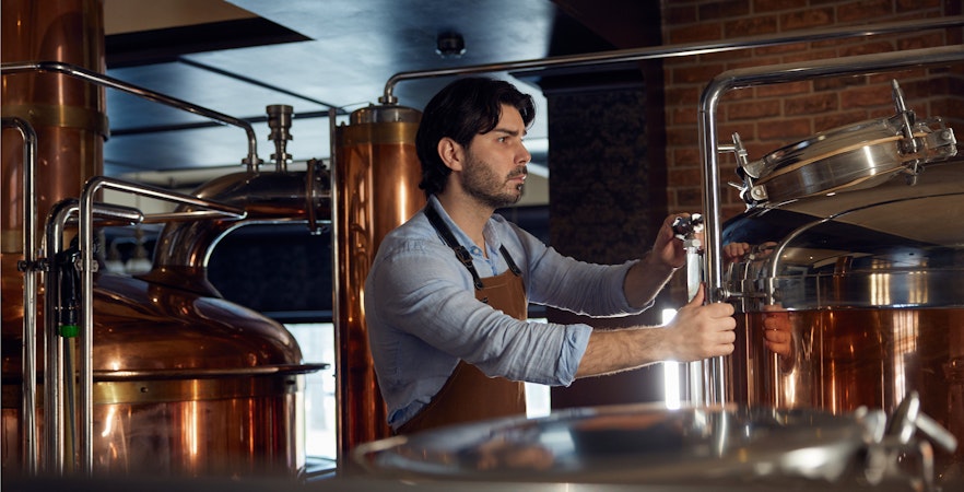 Man operating equipment at a whiskey distillery.