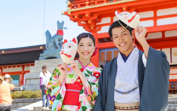 Couple in kimonos holding fox masks at Kiyomizu Temple, Kyoto.