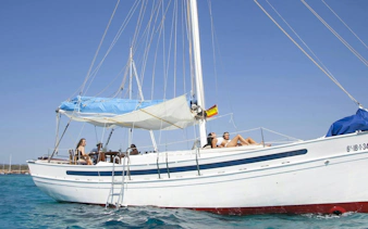 Tourists relaxing on a classic sailboat during a private sunset cruise in Ibiza.