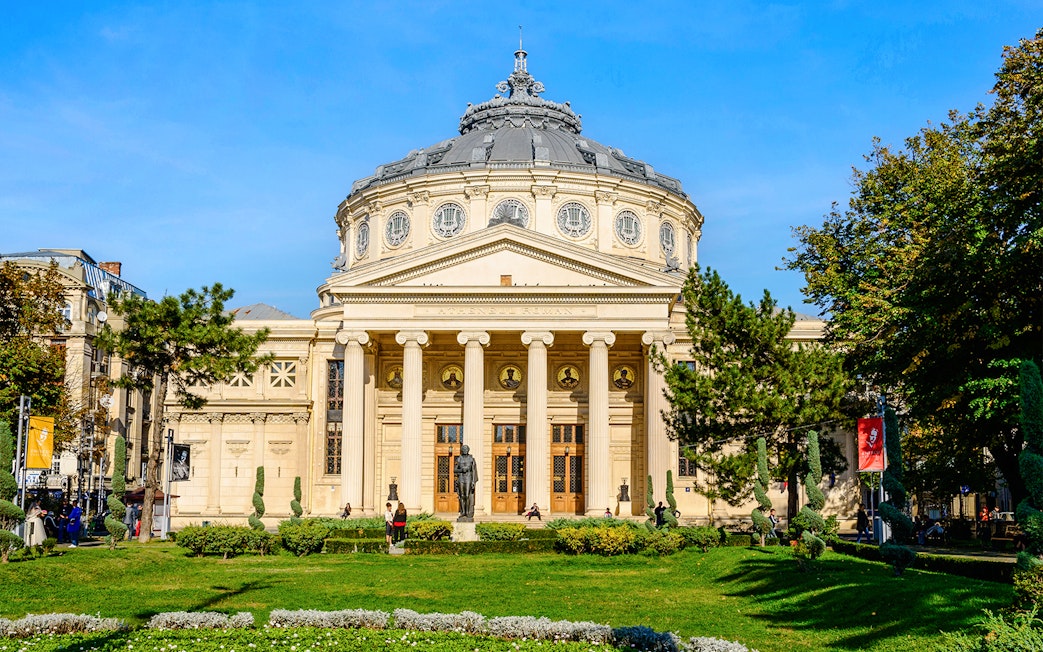 Athenaeum in Revolution Square, Bucharest, with neoclassical columns and garden in foreground.