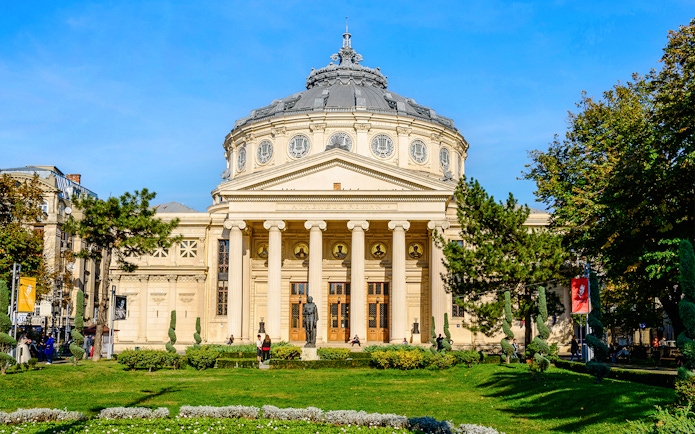 Athenaeum in Revolution Square, Bucharest, with neoclassical columns and garden in foreground.
