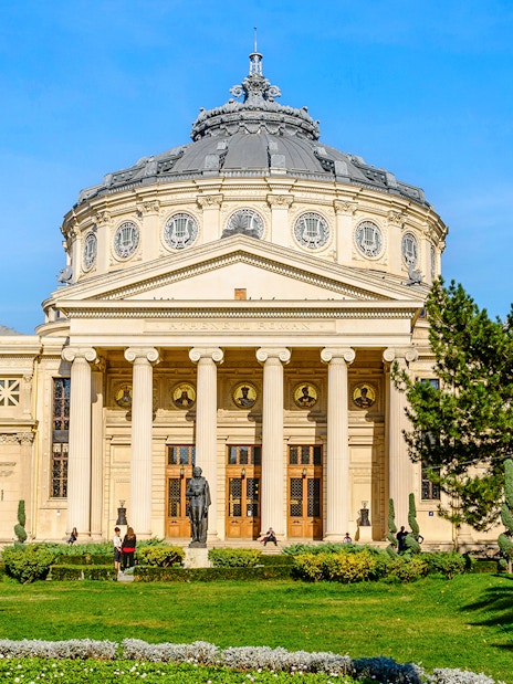 Athenaeum in Revolution Square, Bucharest, with neoclassical columns and garden in foreground.