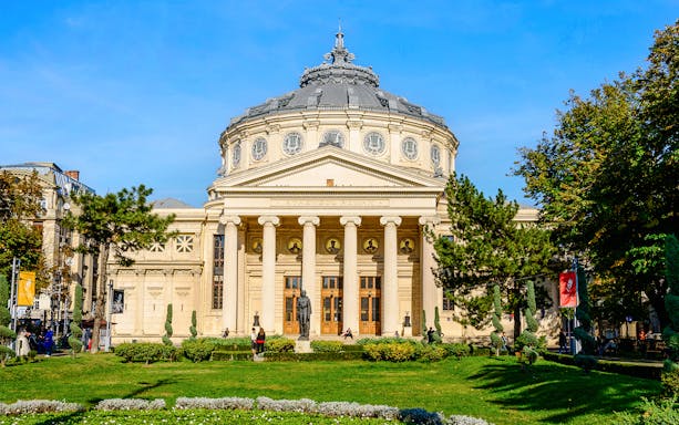 Athenaeum in Revolution Square, Bucharest, with neoclassical columns and garden in foreground.