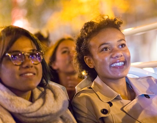 Passengers on the Big Bus Paris Panoramic Night Bus Tour viewing illuminated city.