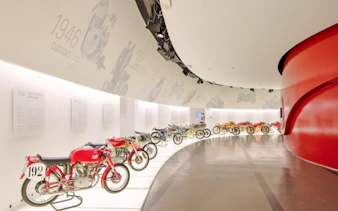 Vintage Ducati motorcycles displayed in a curved gallery at the Ducati Museum, Bologna.