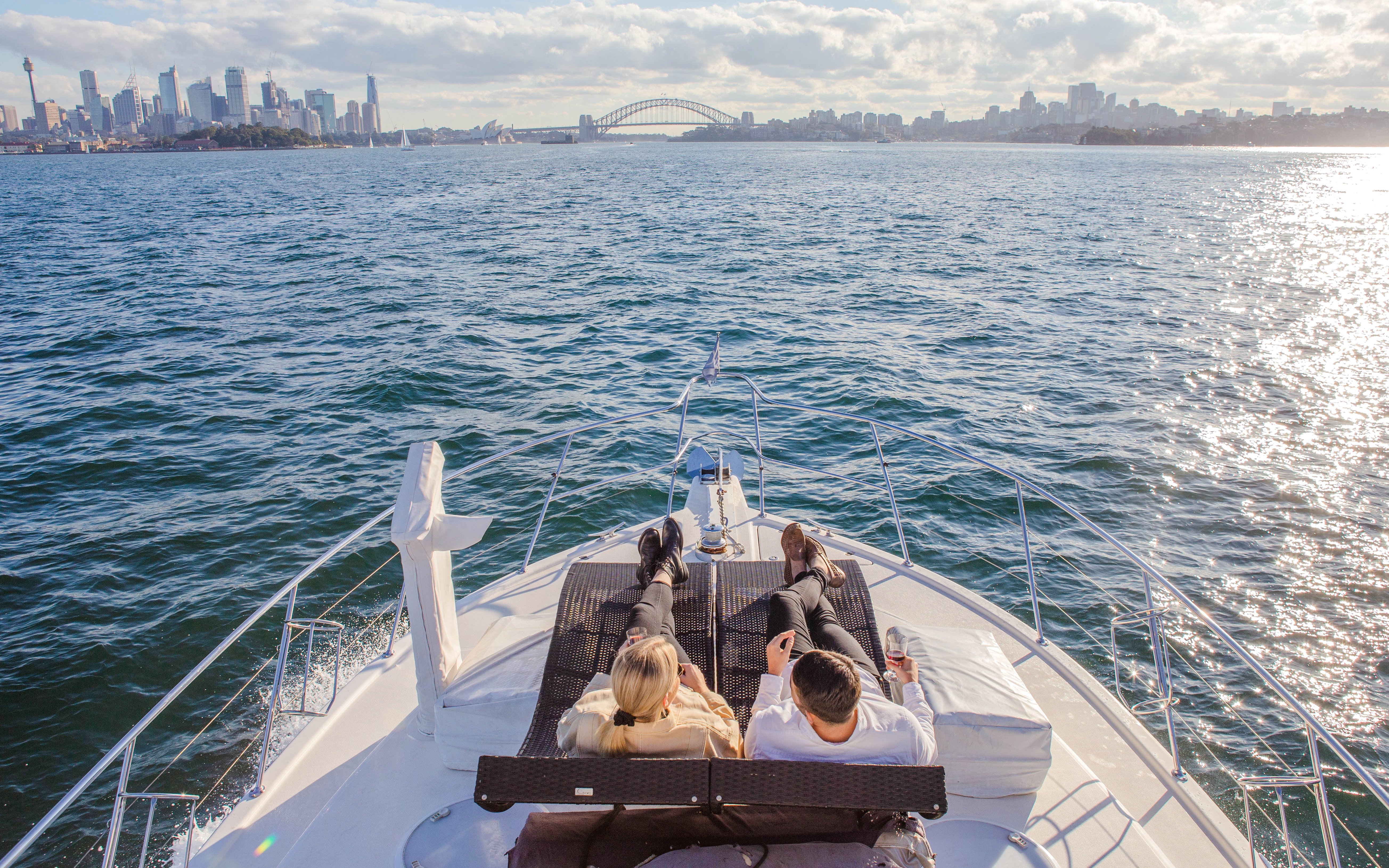 Couple relaxing on a yacht with views of Sydney Harbour Bridge and Opera House.