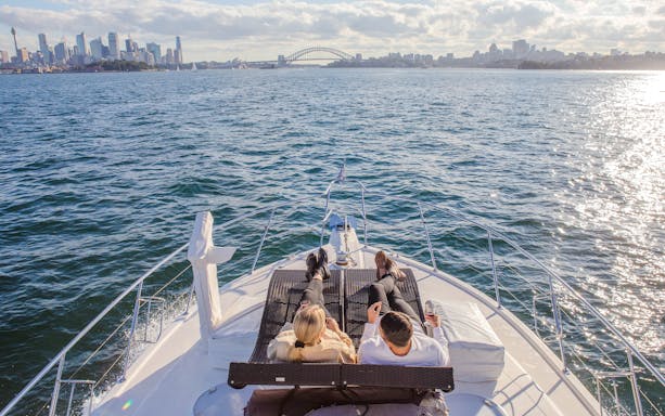Couple relaxing on a yacht with views of Sydney Harbour Bridge and Opera House.