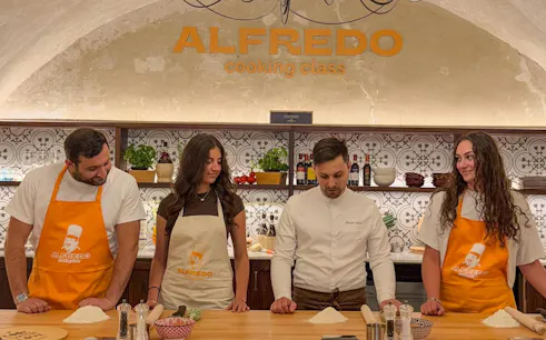 Participants in a Florence pasta-making class with a chef, preparing dough on a wooden table.