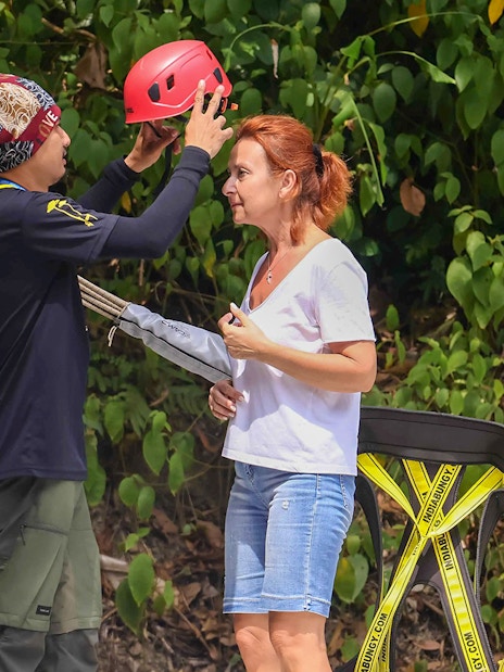 Guide assisting woman with helmet at Hanuman World zipline adventure.