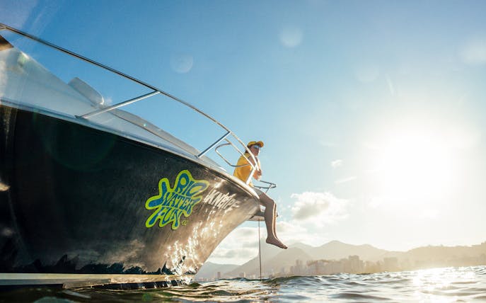 Tourist on speedboat enjoying Rio de Janeiro skyline during a sunny day.