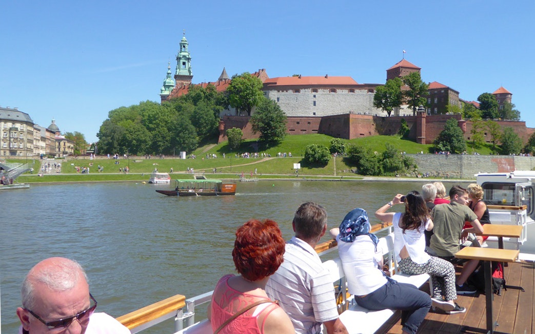 Tourists on a Vistula River cruise viewing Wawel Castle in Krakow.