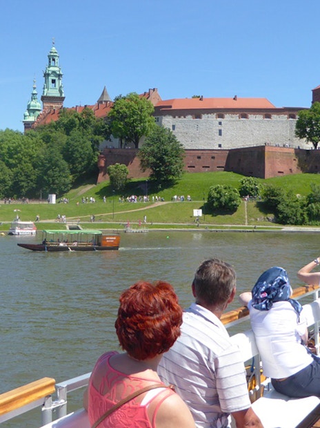 Tourists on a Vistula River cruise viewing Wawel Castle in Krakow.