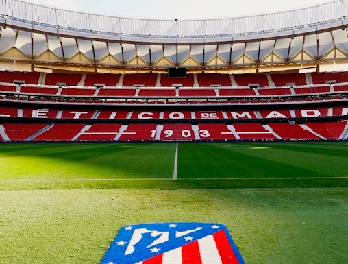Atlético de Madrid Stadium in Madrid, empty red seats and green field.