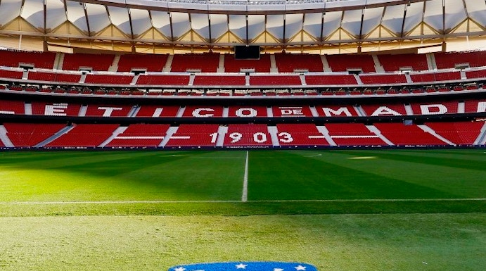 Atlético de Madrid Stadium in Madrid, empty red seats and green field.