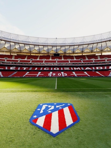 Atlético de Madrid Stadium in Madrid, empty red seats and green field.