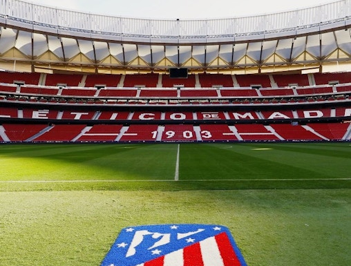 Atlético de Madrid Stadium in Madrid, empty red seats and green field.
