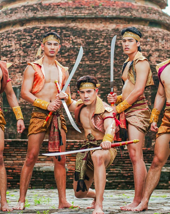 Traditional Thai warriors in historical attire with swords at an ancient temple in Ayutthaya, Thailand.