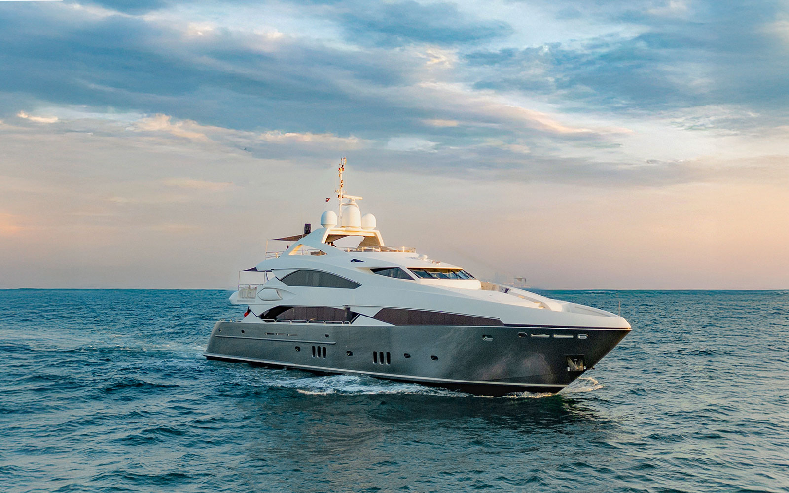 Sunseeker superyacht cruising at sunset, offering gourmet dining and live music experience.