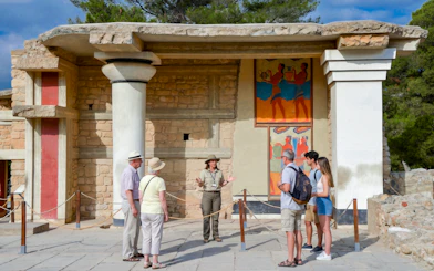 Tour group with guide at Knossos Palace, Crete, viewing ancient frescoes.