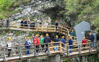 Visitors on a guided tour walking along wooden paths at Vintgar Gorge, Slovenia.