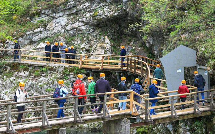 Visitors on a guided tour walking along wooden paths at Vintgar Gorge, Slovenia.