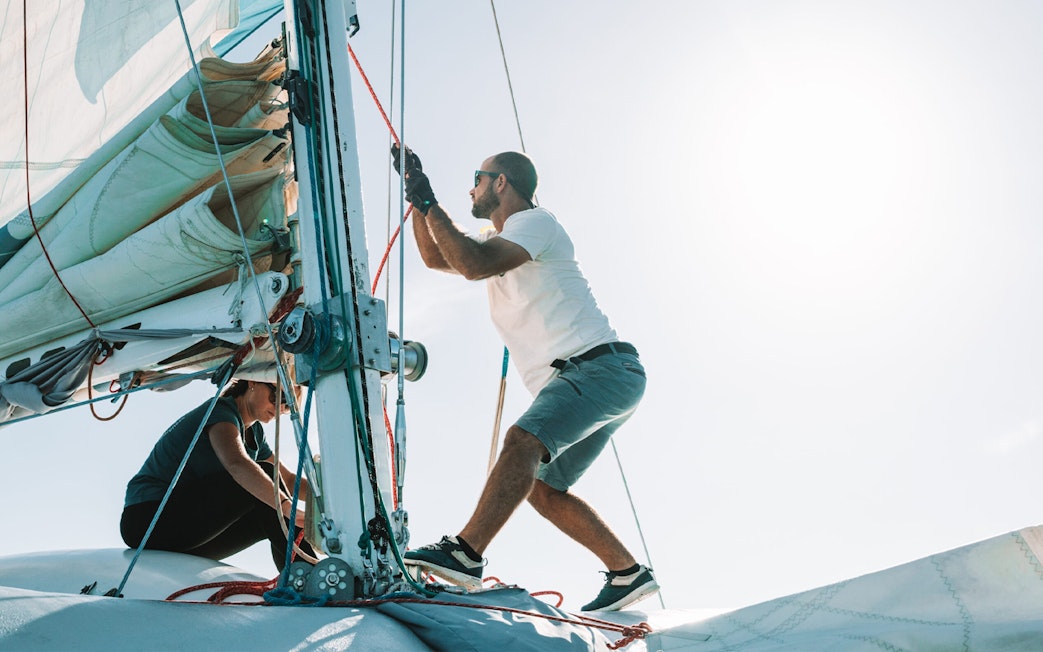 Tourists adjusting sails on a private dolphin watching tour boat.