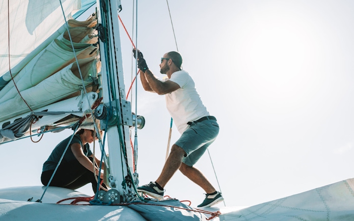 Tourists adjusting sails on a private dolphin watching tour boat.