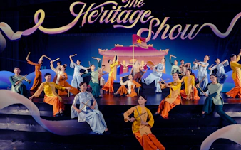 Performers in traditional attire at the Heritage Show, Da Nang, holding bamboo sticks on stage.