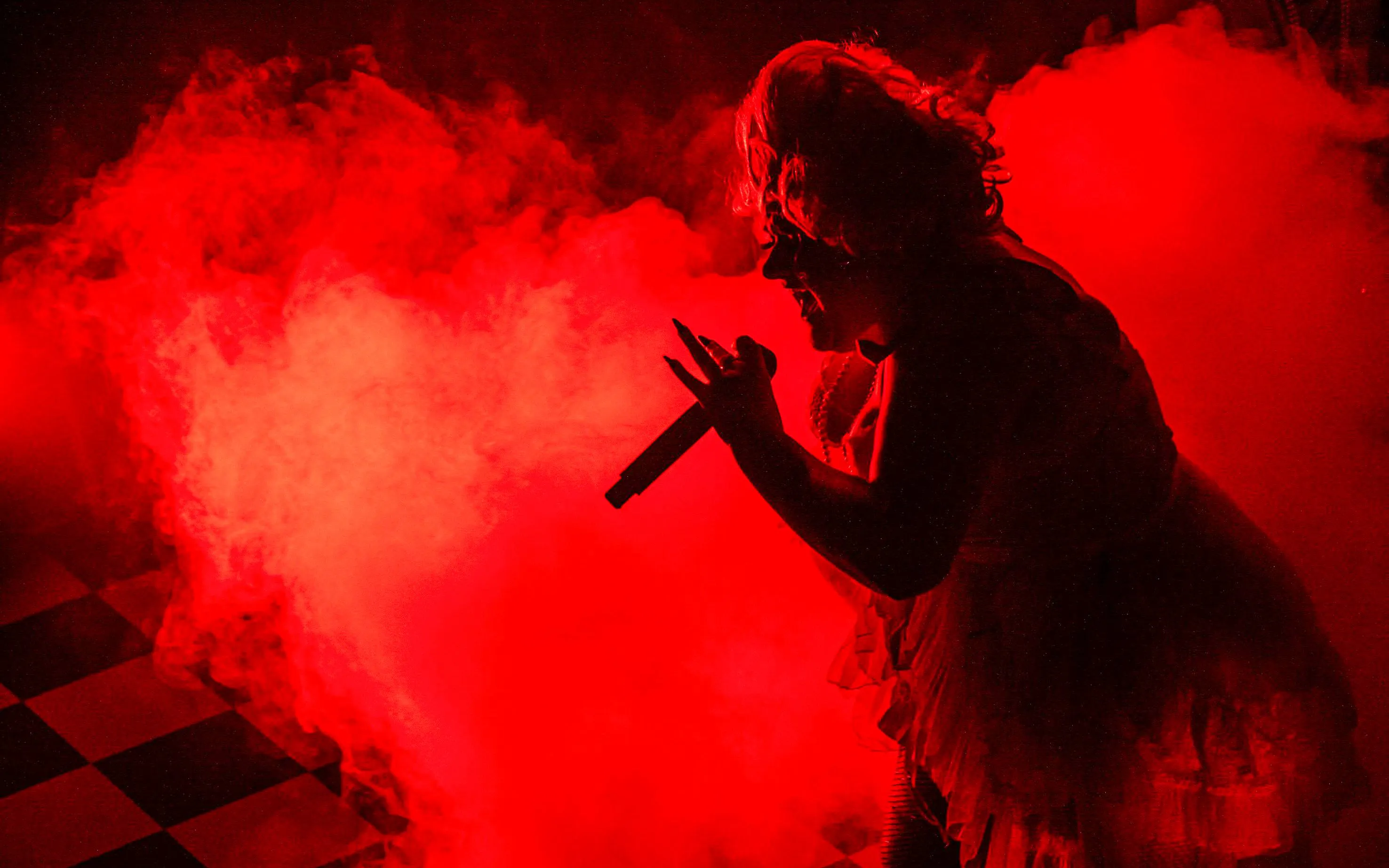 Performer singing at Madame Arthur cabaret show in red stage lighting.