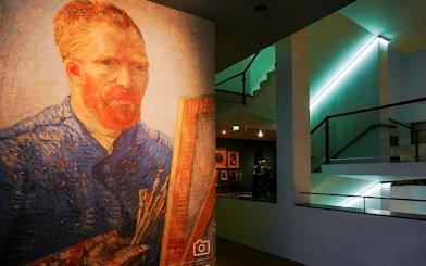 Van Gogh Museum interior with a large self-portrait of Vincent van Gogh displayed.