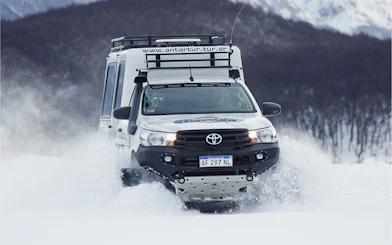 Off-road vehicle driving through snowy terrain during Snow and Fire Night experience.