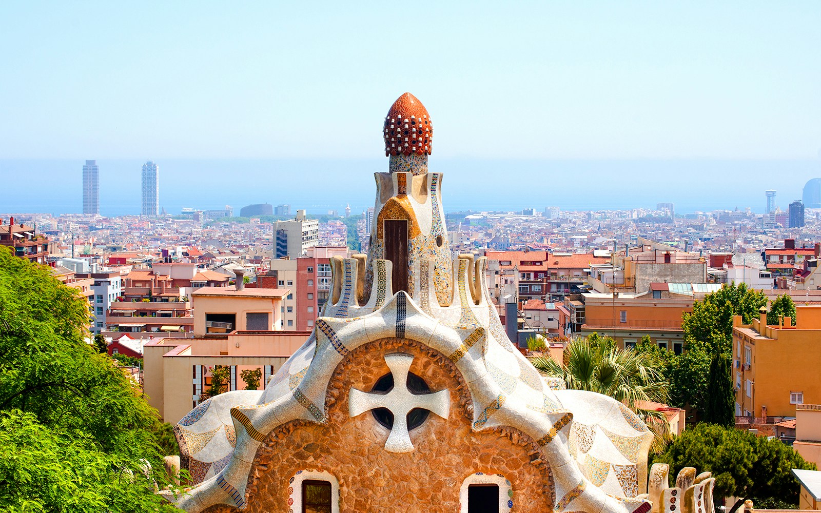 Casa del Guarda rooftop in Park Güell, Barcelona, with cityscape and sea in the background.