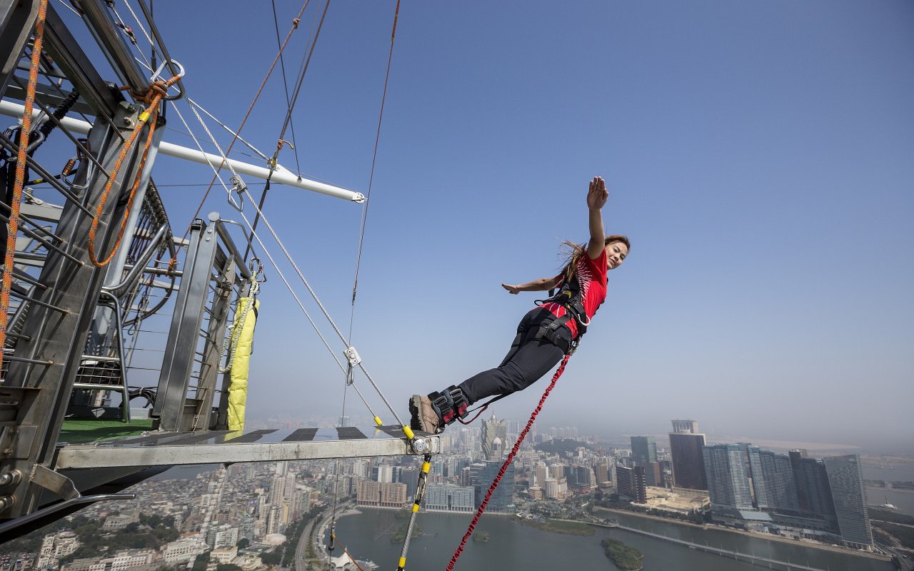 Bungee jumper leaping from Skypark Macau platform with cityscape view.