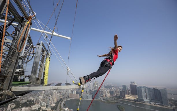 Bungee jumper leaping from Skypark Macau platform with cityscape view.