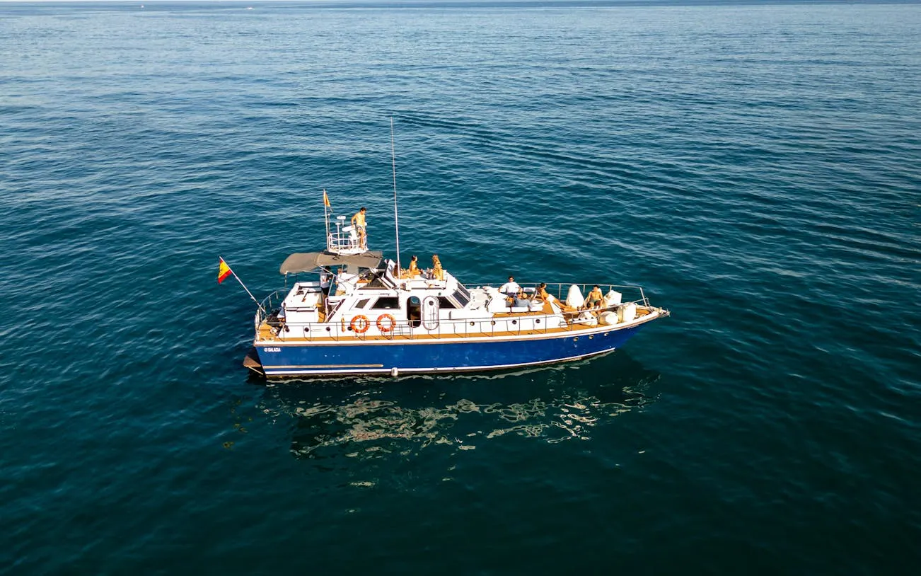 Small group on a boat in Benalmádena for dolphin-watching cruise with snorkeling and paddle surf.