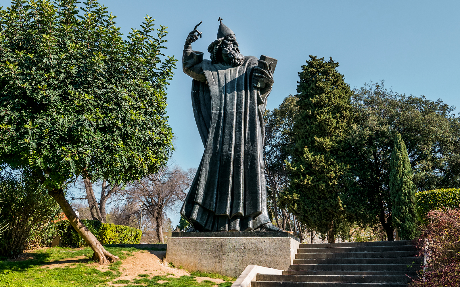 Statue of Grgur Ninski in Split, Croatia, surrounded by trees.