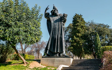 Statue of Grgur Ninski in Split, Croatia, surrounded by trees.