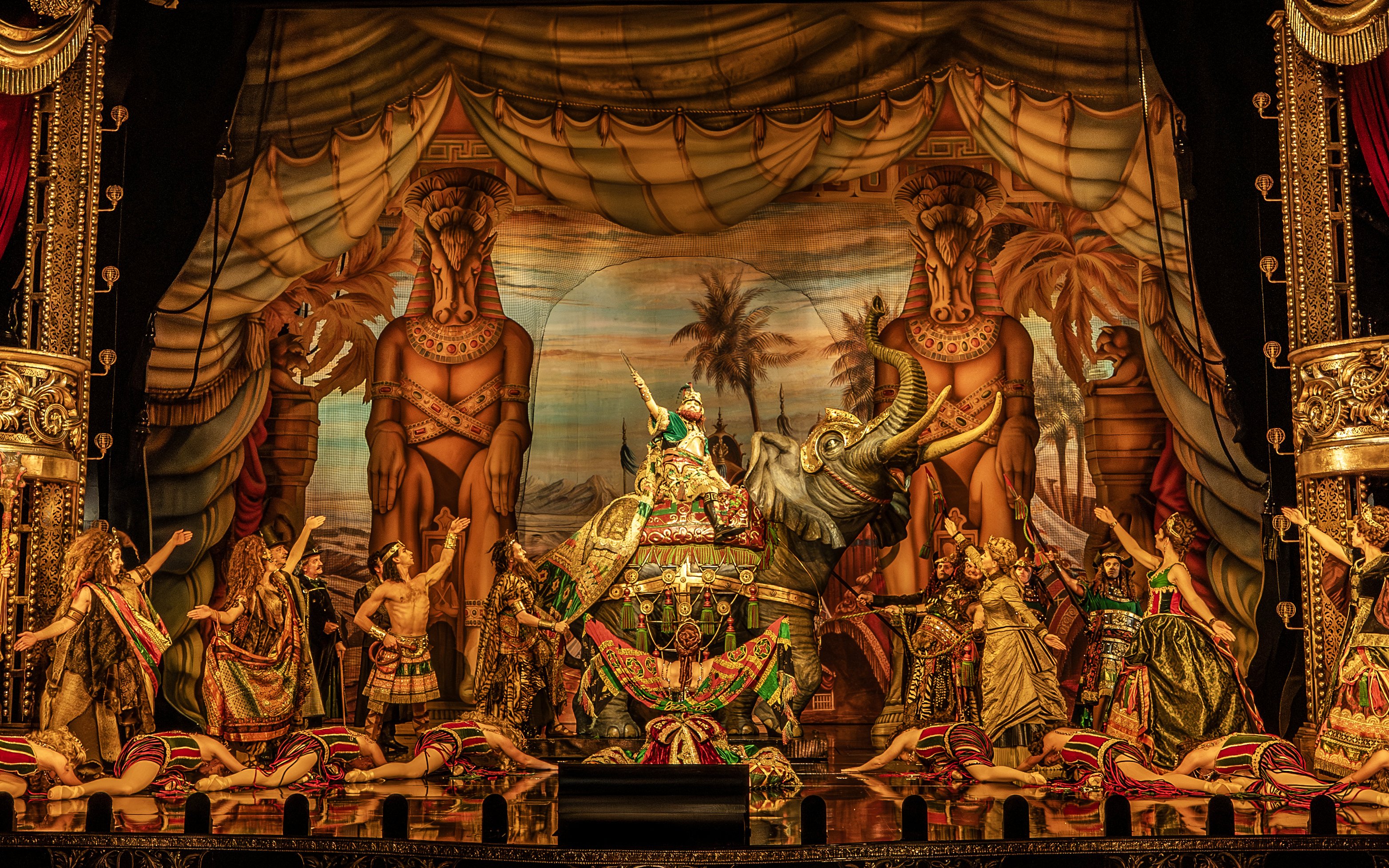 Phantom of the Opera stage scene with performers in elaborate costumes and an elephant prop.