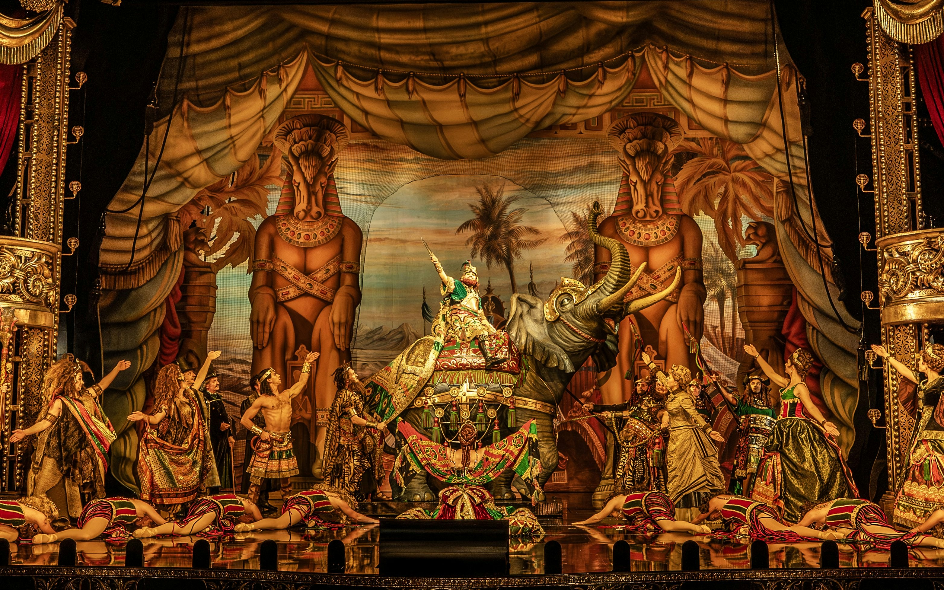 Phantom of the Opera stage scene with performers in elaborate costumes and an elephant prop.