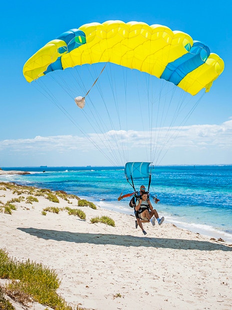 Instructor and guest landing with parachute on Rottnest Island beach.