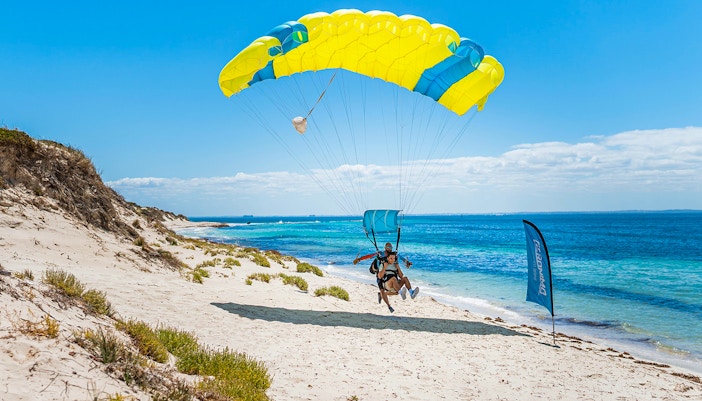 Instructor and guest landing with parachute on Rottnest Island beach.