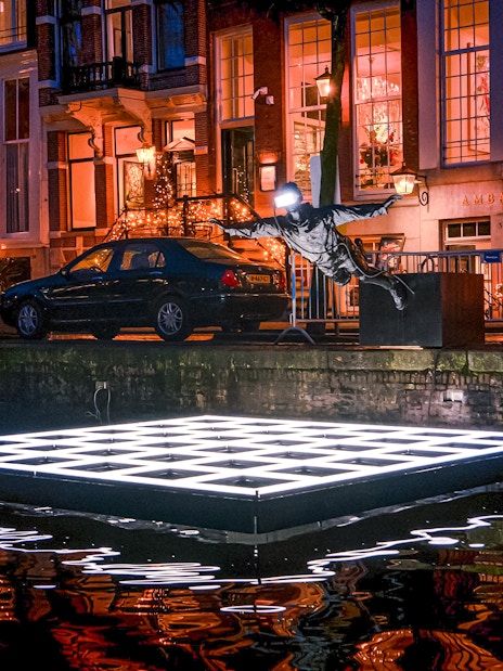 Sculpture and illuminated platform on Amsterdam canal during Light Festival cruise.