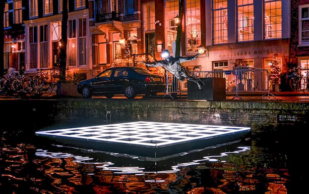 Sculpture and illuminated platform on Amsterdam canal during Light Festival cruise.